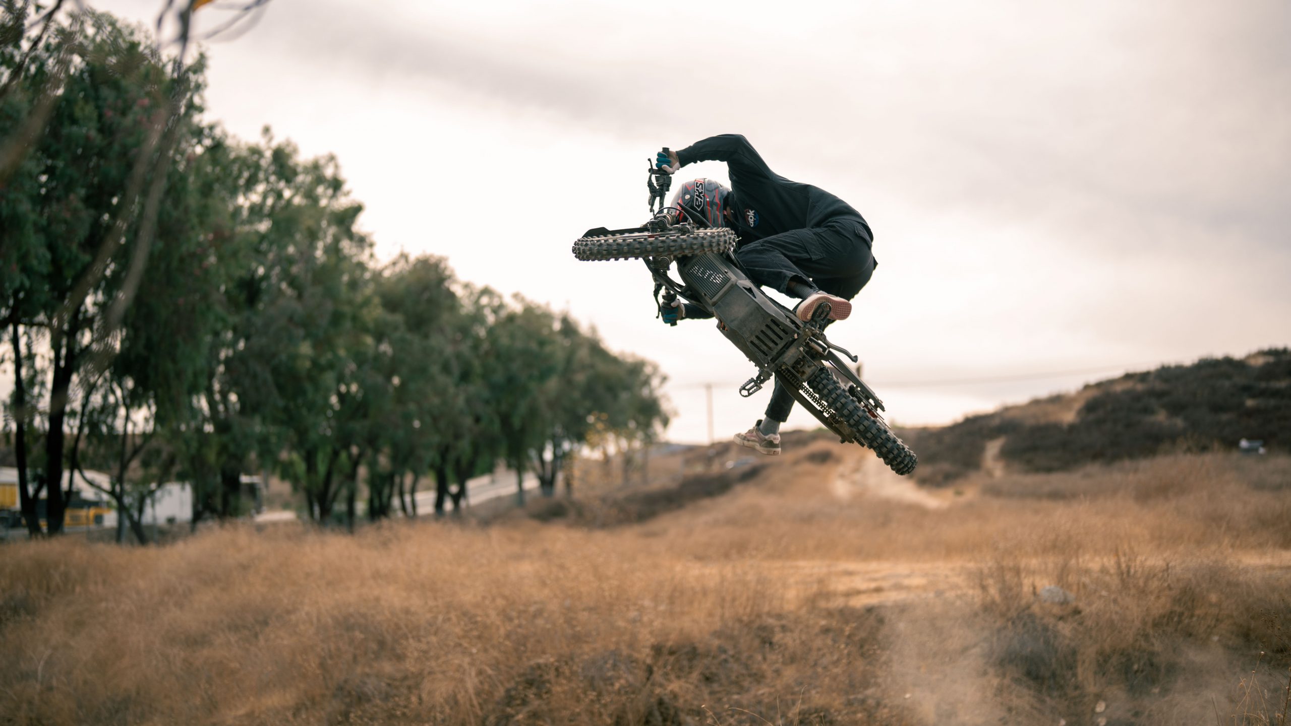Rider performing aerial jump on Altis Sigma electric motocross bike during off-road riding